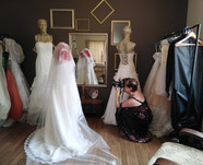 A lady photographer is taking pictures of wedding dresses displayed on mannequins in a sewing studio