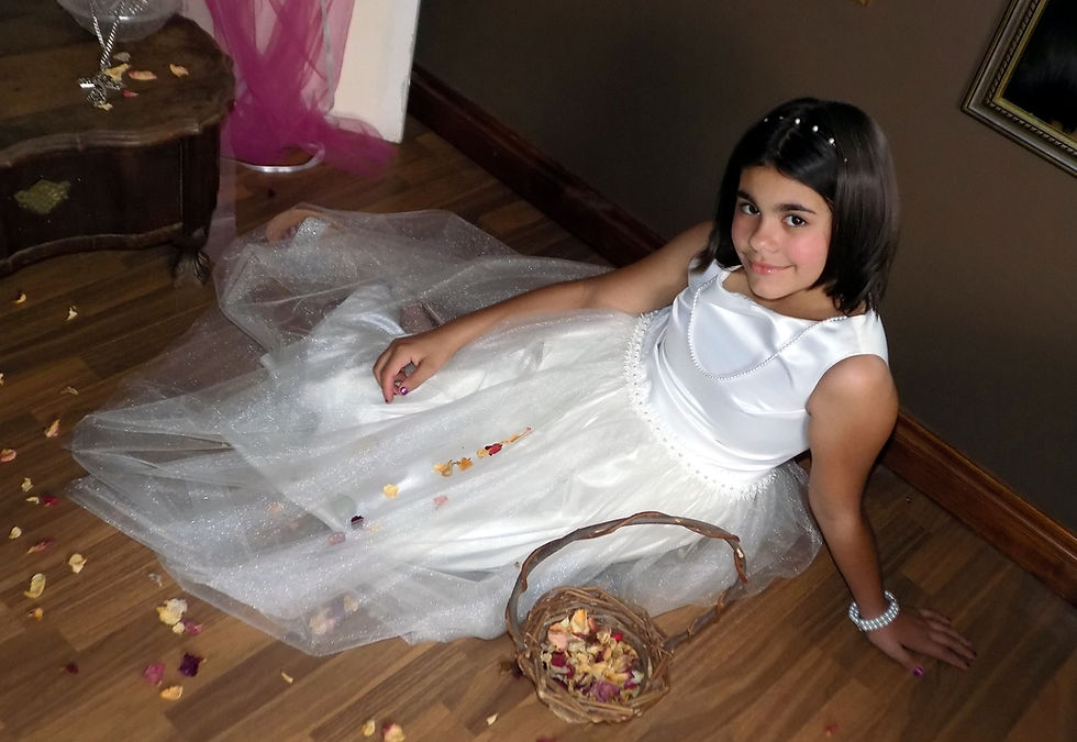 A girl in awhite
dress sitting on the floor among scattered dried rose petals
