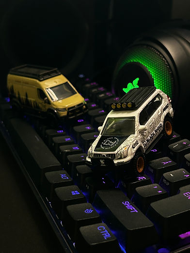 2 Hot Wheels offroad 1:64 scale diecast cars parked on a gaming keyboard