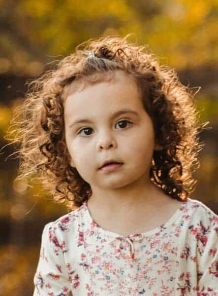 Little girl with curly hair smiles at camera