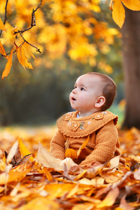 A baby with yellow autumn leaves