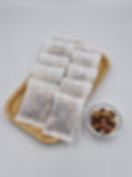 Rejuvenating and beautifying flower tea sachets on plate, loose leaf in clear bowl