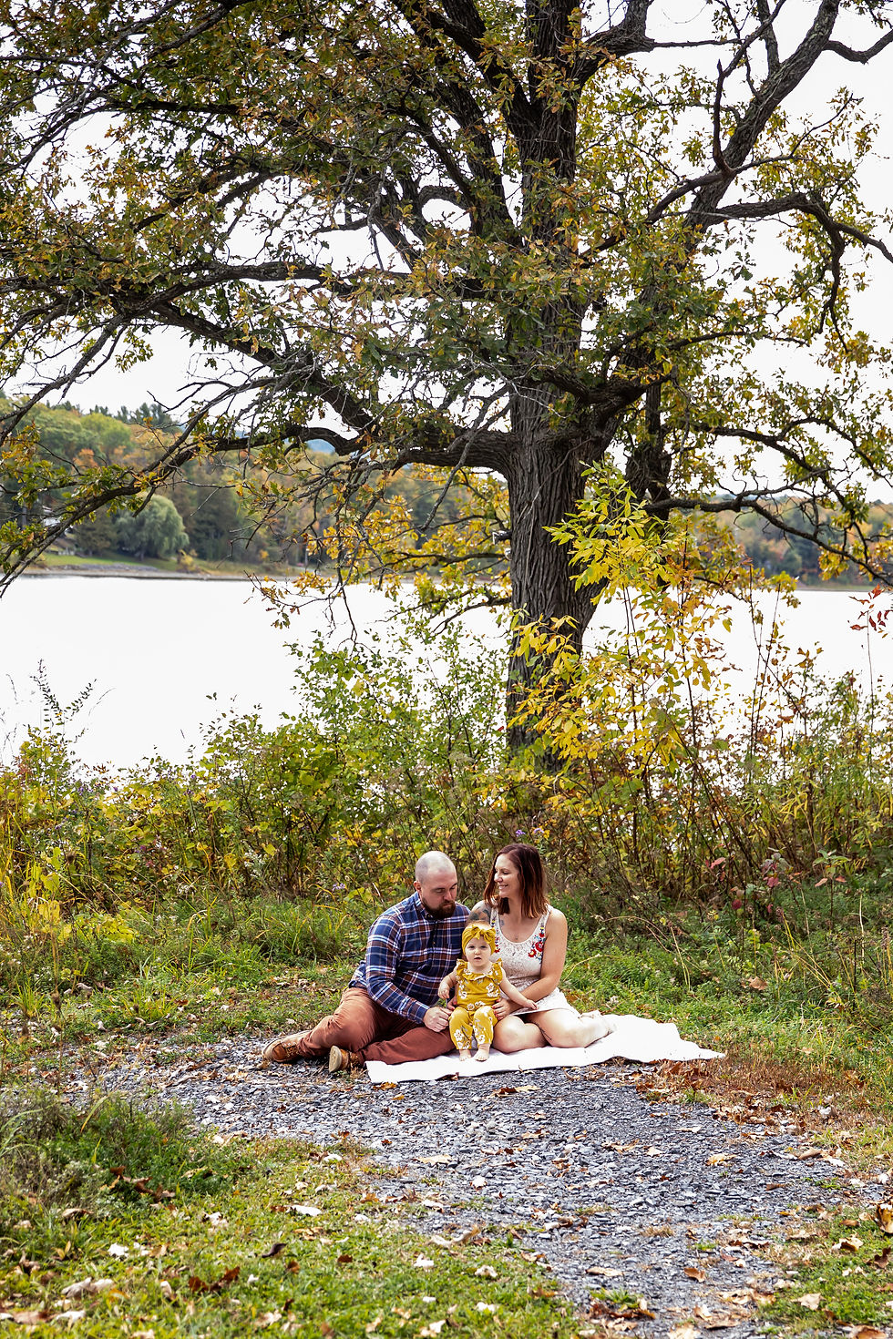 Family portrait shot near lake in the fall. One year old baby girl with mom and dad
