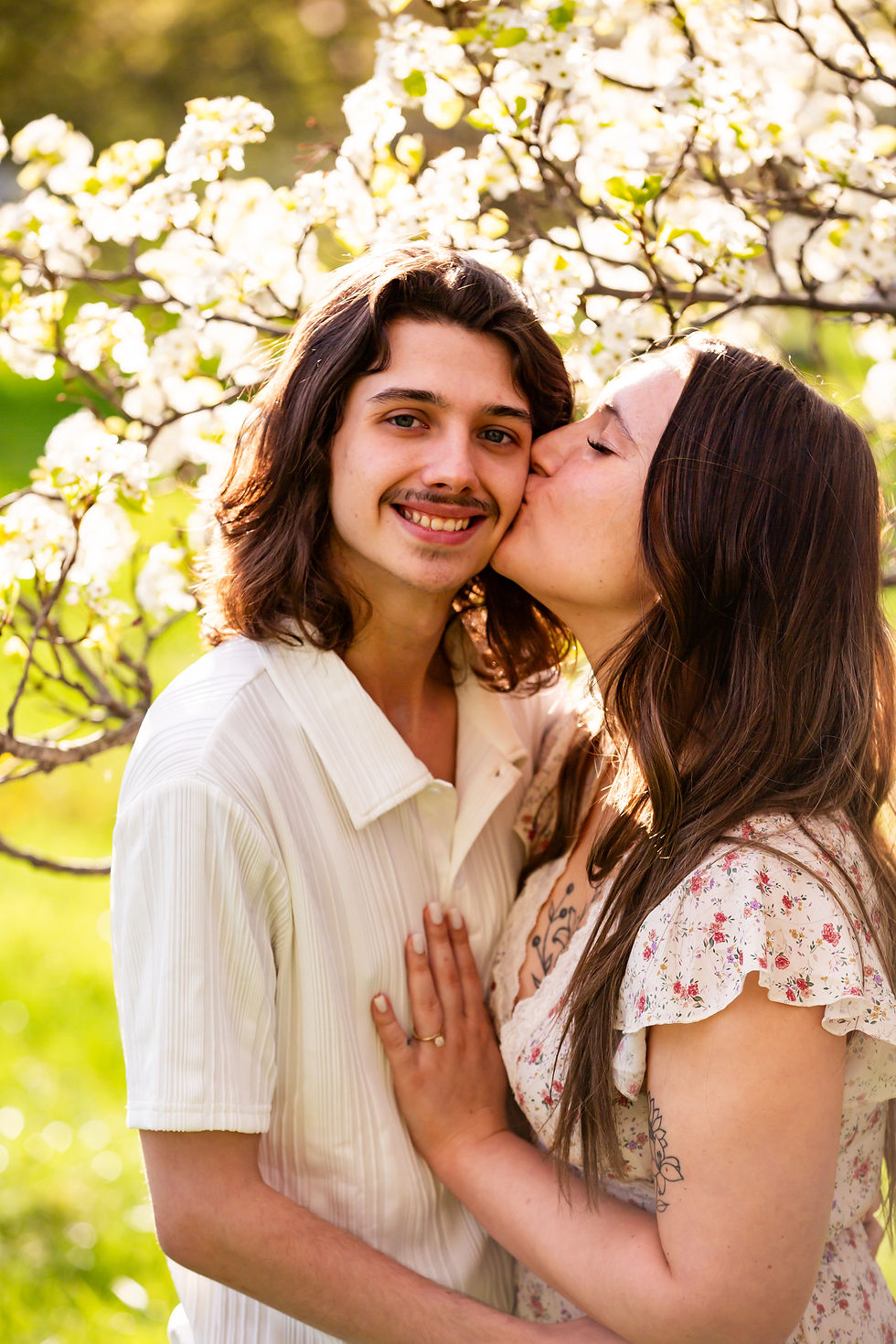 engaged couple in spring session with white flowering pear trees