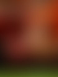 A woman laying on her back in the gym doing core exercises while smiling.