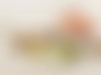 Um abacate partido ao meio, pote com azeite, pote com nozes, duas colheres de pau com especiarias e um pedaço de salmão in natura, tudo sobre uma mesa de madeira clara.