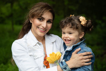 mother weaing white denim , toddler in blue denim, flowers in hand