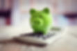 Green piggy bank sitting on top of a calculator