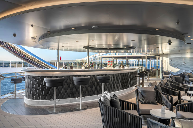Sophisticated open-air lounge on MSC/Explora Journeys cruise liner with plush seating and a panoramic view.