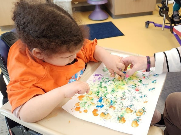 A young girl paints using a small sponge