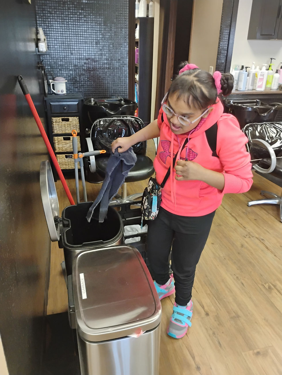 A young woman taking a dirty towel out of the bin at a local hair salon in Aberdeen, SD, as part of her job skills training