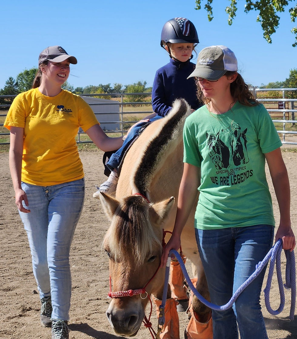 A young girl riding her horse Zeva at SPURS with her teacher as her sidewalker