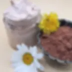 słoiczek krówkowego masła do ciała na jasnym tle w otoczeniu kwiatów i kakao umieszczonego w ozdobnym ceramicznym naczyniu