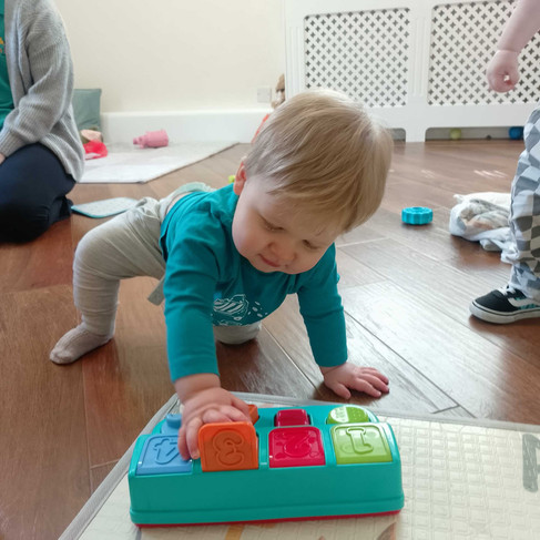 a baby boy pressing buttons on a pop up toy
