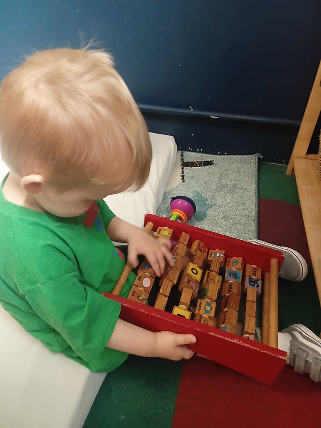 a little boy is focusing on an ABC board, exploring the letters by turning the pieces