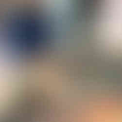 a black haired little boy is playing with cooked spahgetti and colourful papershapes, making a face in a black sensory tray