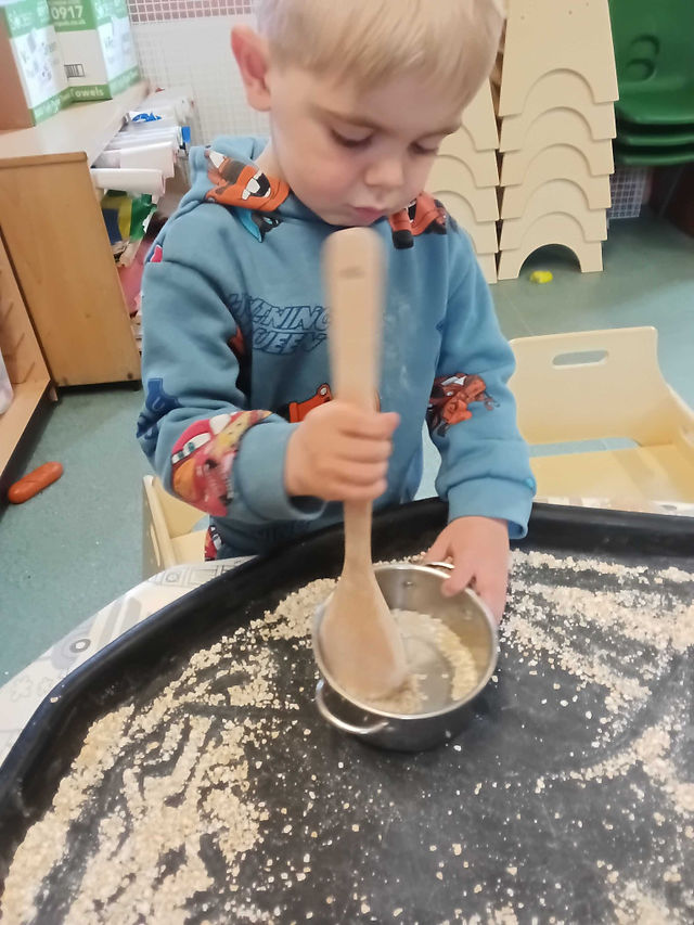 a little boy is stirring a bowlful of porridge oats