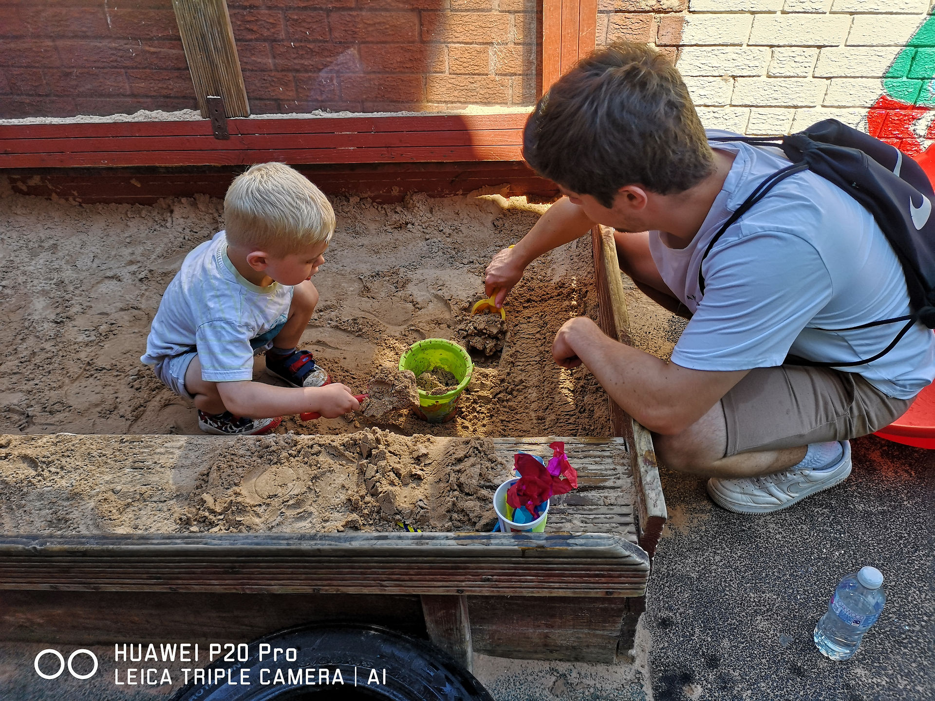 a dad is helping his little son to build a sand castle in the sand pit at Fun Box Day Nursery