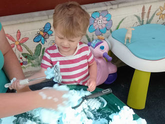 a young toddler is exploring foam with a help of a practitioner