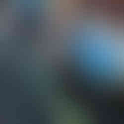 a little toddler and another child behind him balancing on some beans next to a blue table in a nursery garden