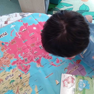 A child looking closely at a colourful world map while exploring different countries