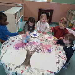 young children are creating a blossoming tree using paint and plastic bottles