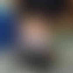 a little girl is sitting on the floor, holding up a knitted caterpillarm there is a cozy corner in the background with different cushions