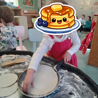 a little girl is placing a paper pancake into areal pan in a sensory tray filled with paper pancakes, flour and pans