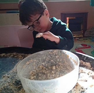 a little boy wearing glasses is mixing a bowl of porridge 