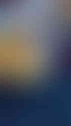 a toddler is bending over a large, yellow triangular shaped tray that has dried, colourful leaves in it