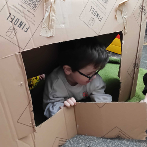 a little boy wearing glasses are hiding in a big cardboard box