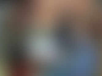 three children are in intense conversation about a book they are looking at sitting on a colourful carpet