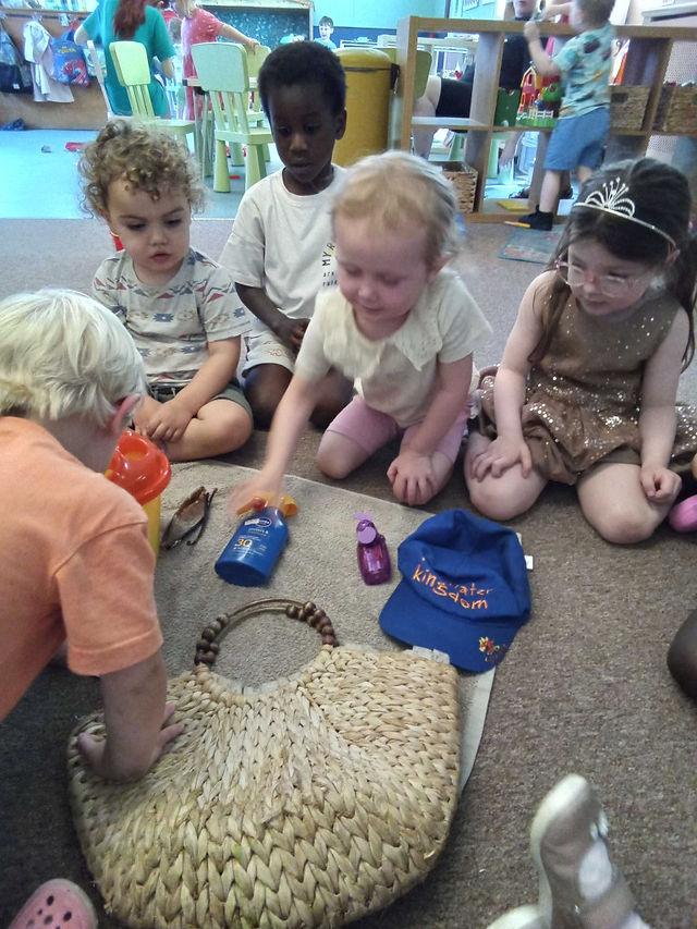 a group of young children are sitting on a carpet, looking at holiday related objects