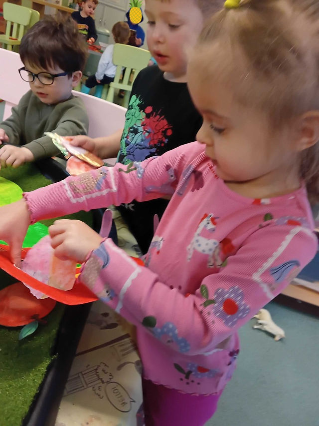 a little girl is feeding a toy food into the mouth of a Very hungry Caterpillar stencil