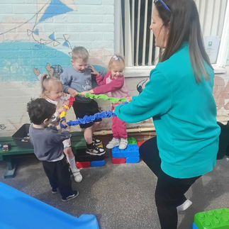 a group of small children are pulling on an expandable band held by a teacher