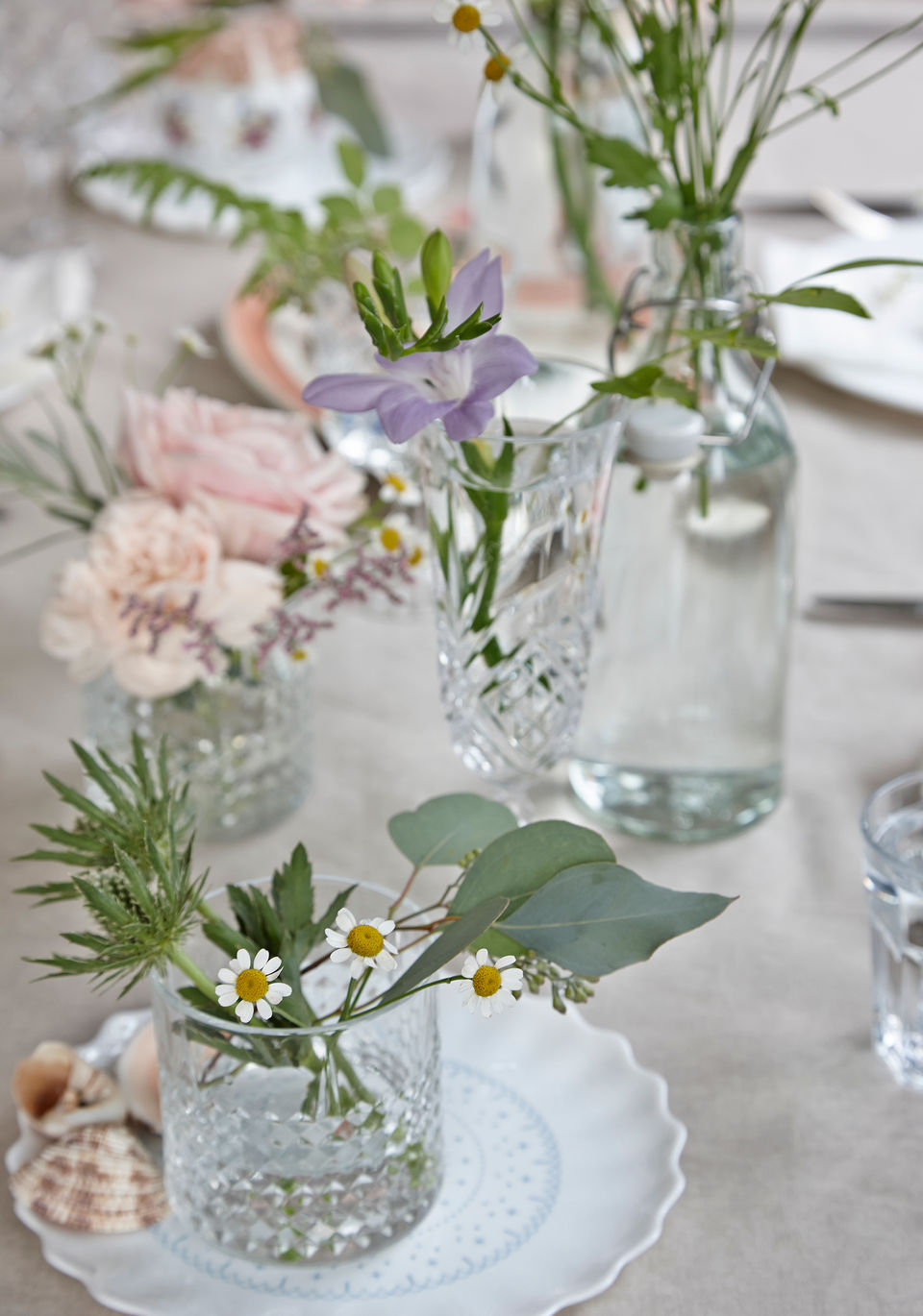 image of glass vases  with flowers from ikea in a table setting on a light tan table cloth