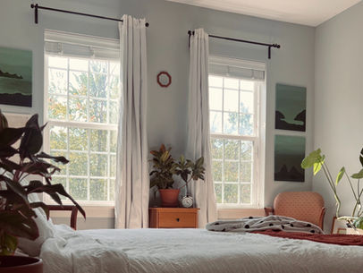a bedroom decorated with plants and wall art with a midcentury modern style