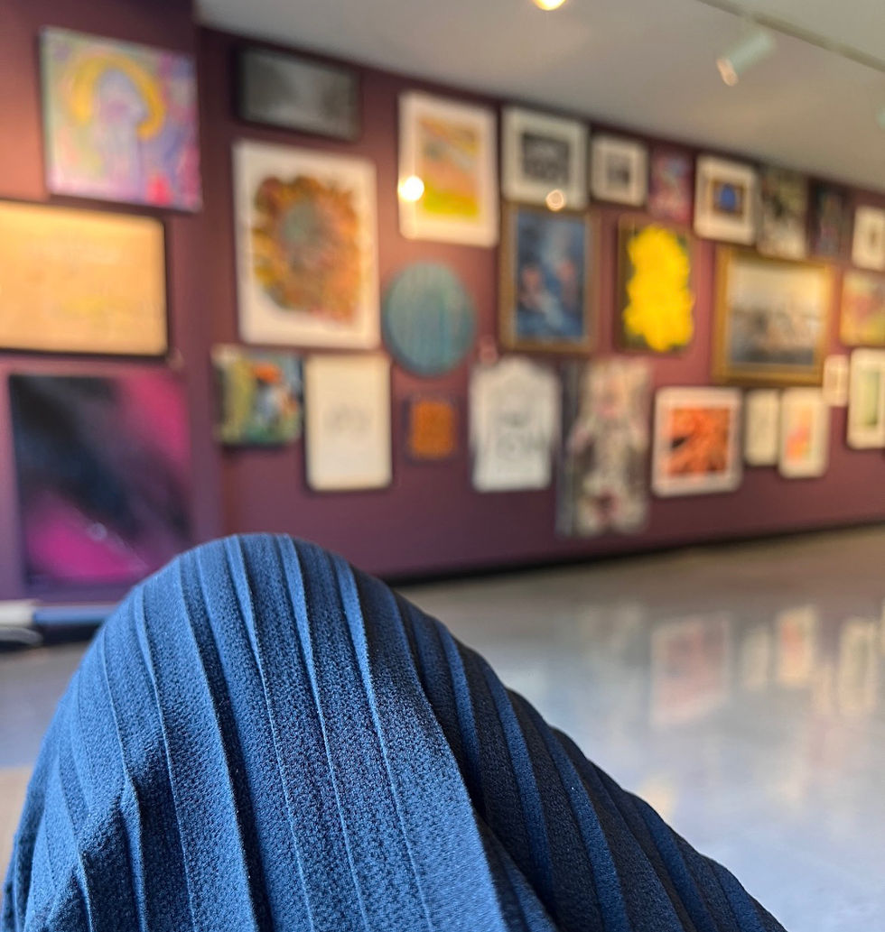 woman sitting looking at a wall of art