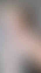 A close-up, off-the-shoulder portrait of a model with a blonde quiff hairstyle, wearing a deconstructed, textured corset top in beige and blue