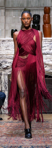 Model in a sleeveless red fringe dress with cutouts at the torso and a thigh-high slit, walking the Ahluwalia SS26 runway at NoMad London.