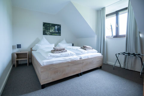 Gemütliches Doppelbett im Gästehaus, helle Wände