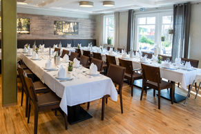 Festlich gedeckte Tische in einem hellen Speisesaal.