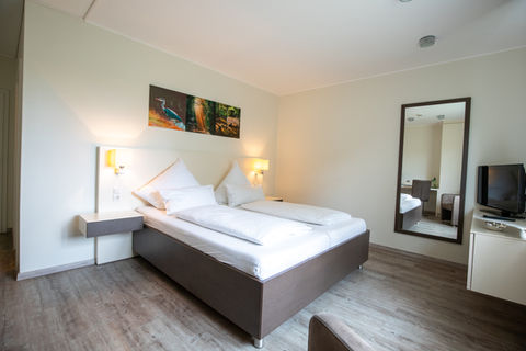 Helles Hotelzimmer mit Doppelbett und Spiegel