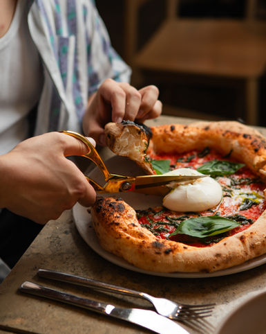 Person schneidet Pizza mit Schere