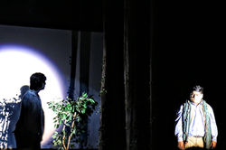 The Baker (Jacob Lara) in a spotlight, with his father (Chris Miller) forming his shadow.
