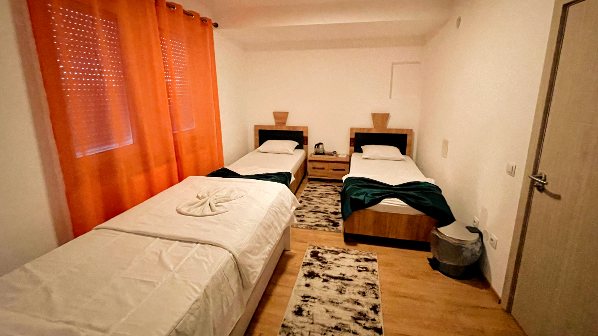 Room 101 bedroom with single beds, green runners and orange curtains
