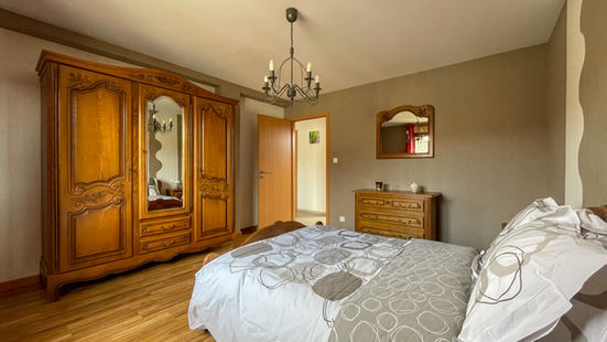 Bedroom with a large carved wooden wardrobe at the Le Foulon gîte.