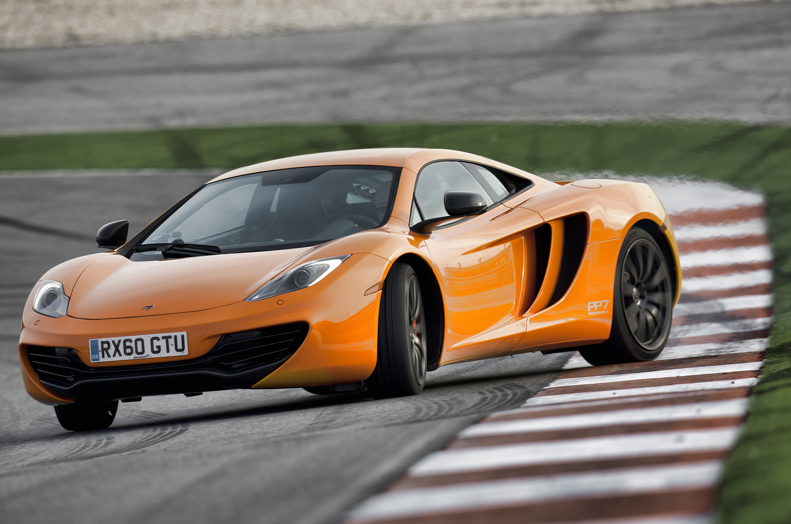 McLaren MP4-12C in orange cornering on a racing circuit