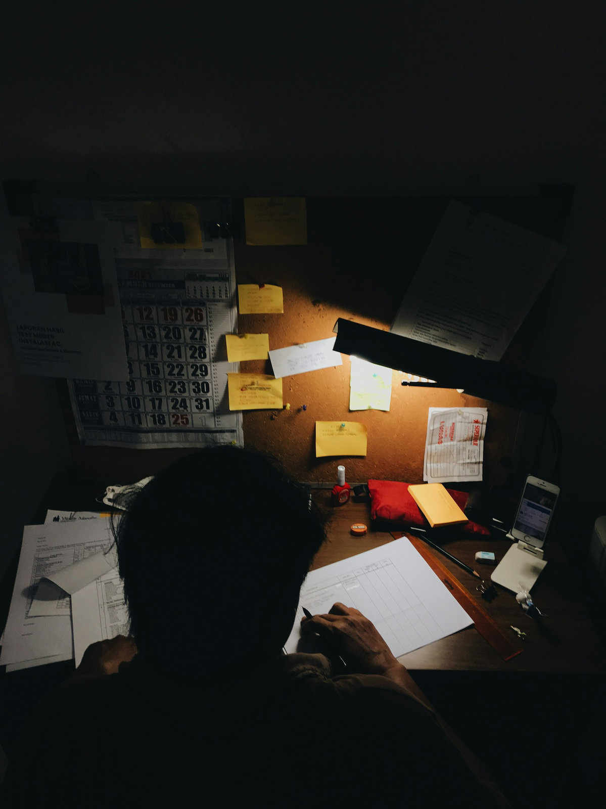 A student working at a desk under a lamp at night