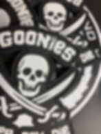 Glow-in-the-dark “The Goonies” PVC patch featuring skull-and-crossbones design with hook backing.